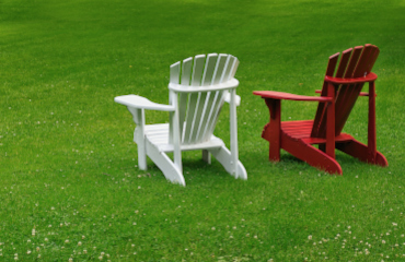 Ein weißer und ein roter Gartenstuhl nebeneinander, wie ein Paar in der Paartherapie Paderborn