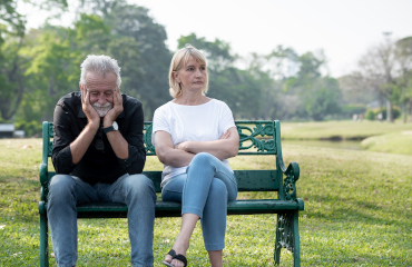 Ein Paar sitzt auf einer Parkbank. Sie schauen sich nicht an.