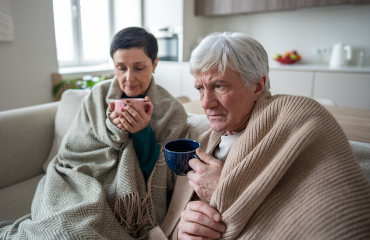 Erschöpftes Paar sitzt mit Abstand auf dem Sofa – Rückzug bei Überlastung