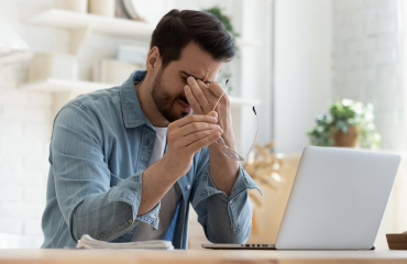 Nachdenklicher erschöpfter Mann vor dem Laptop 