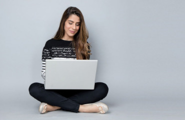 Frau im Schneidersitz mit einem Laptop auf den Schoß - Online Beratung und Therapie Essstörungen