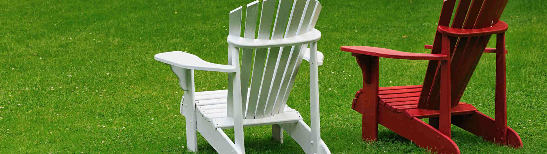 Ein weißer und ein roter Gartenstuhl stehen auf einer Wiese - Paartherapie Paderborn