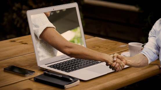 Hand aus dem Laptop schüttelt die Hand eines Mannes - Unterstützung Angehörige von Essgestörten