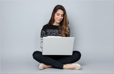Frau sitzt bequem im Schneidersitz - Laptop auf den Knien - Online-Vorträge